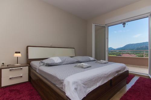 a bedroom with a bed and a large window at Holiday Home Vele with pool in Vrgorac