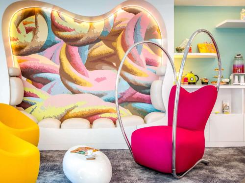 a room with a chair and a colorful wall at ibis Styles Fréjus St Raphael in Fréjus