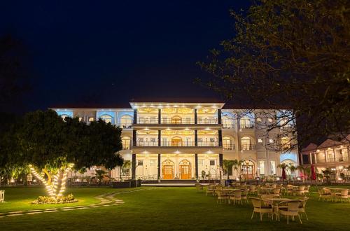 a large building with tables and chairs at night at The Lychee Hotel & Resort by The Altruist in Rāmnagar