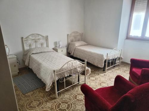 a bedroom with two beds and a couch and a chair at Oasi Relax Lago Omodeo Casa Demartis in Tadasuni