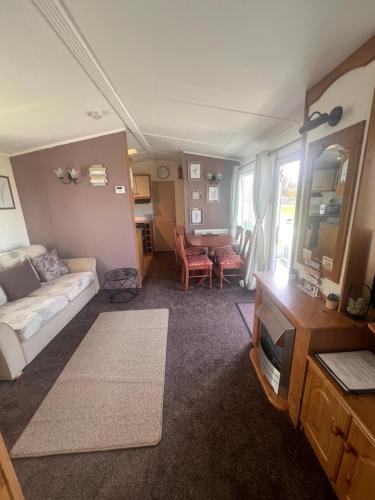 a living room with a couch and a tv in it at A7 caravan The Chase Ingoldmells in Ingoldmells