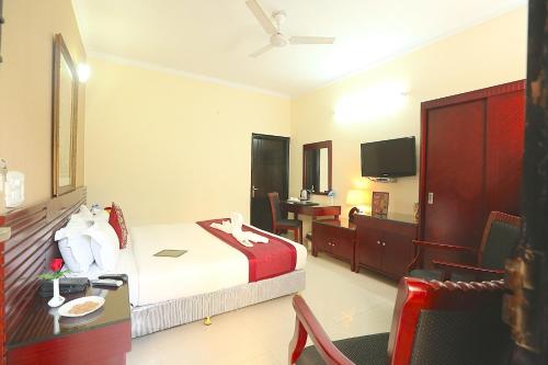 a hotel room with a bed and a desk and a television at Hotel Kridha Residency - Opposite Prem Mandir Vrindavan in Mathura
