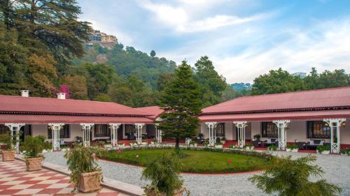a building with a checkered courtyard with trees and a mountain at The Claridges Nabha Residence in Mussoorie