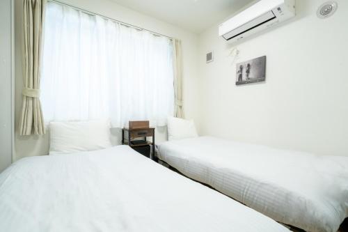two beds in a room with a window at Laguna Verde Misono 103 in Sapporo