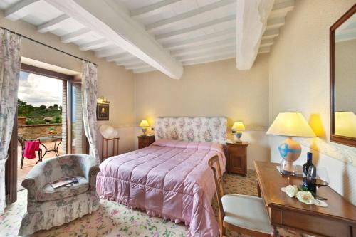 a bedroom with a bed and a table and a chair at Relais Il Canalicchio Country Resort & SPA in Canalicchio