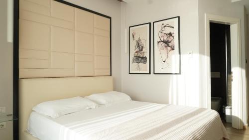 a bedroom with a white bed with two pictures on the wall at Hotel Miami II in Golem