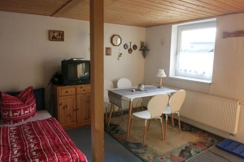 フラウエンヴァルトにあるWanderunterkunft in Frauenwaldのテーブルと椅子、テレビが備わる客室です。