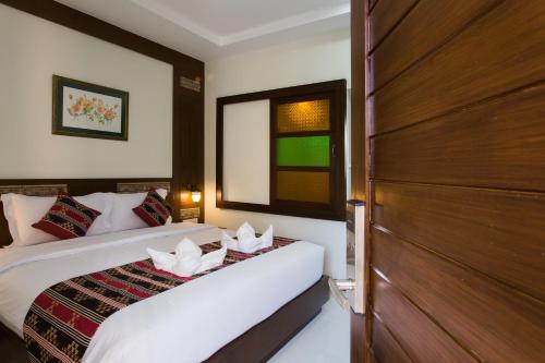 a bedroom with two beds and a wooden door at Mhonsa Hotel in Chiang Mai