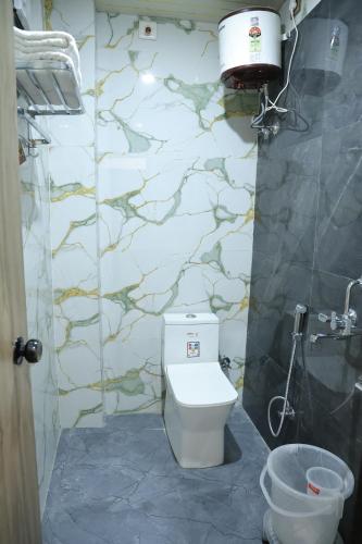 a bathroom with a toilet and a stone wall at Hotel Krishna Residency in Udaipur