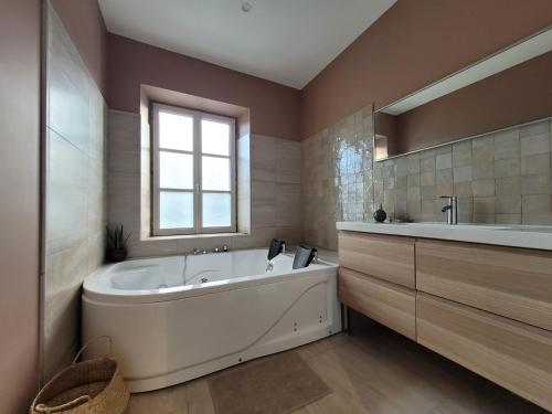 ein großes Badezimmer mit einer großen Badewanne und einem Fenster in der Unterkunft leon in Landerneau