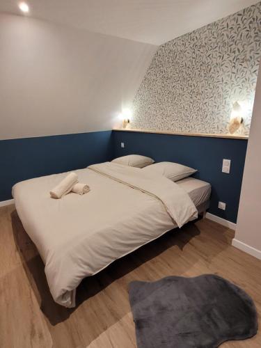 ein Schlafzimmer mit einem großen weißen Bett und einer blauen Wand in der Unterkunft leon in Landerneau