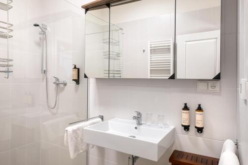 a white bathroom with a sink and a shower at BHG Apartments Prague in Prague