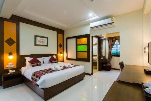 a bedroom with a large bed and a desk at Mhonsa Hotel in Chiang Mai