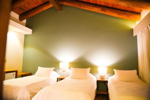 two beds in a room with a green wall at Hostería La Bordona in Rivera