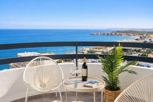 a table with two chairs and a bottle of wine on a balcony at Casa Ivo OceanView in Portimão