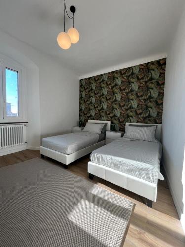 two beds in a white room with a wall at Art Residency Borgo Castello in Gorizia
