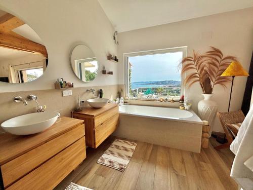 a bathroom with two sinks and a tub and a window at Villa Horizon Bleu in Sainte-Maxime