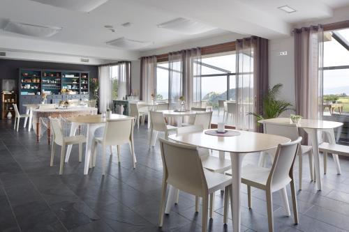 a restaurant with white tables and chairs and windows at Hotel San Prudentzio in Getaria