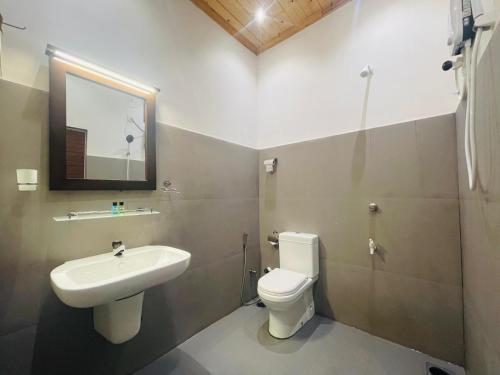 a bathroom with a sink and a toilet and a mirror at J Hotel in Jaffna