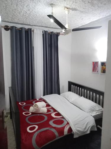 a bedroom with a bed with a red and white blanket at TN Apartments Adina in Diani Beach