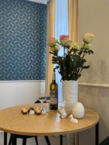 a table with a vase of roses and a bottle of wine at Apartamenty Klasztorna 25 in Poznań