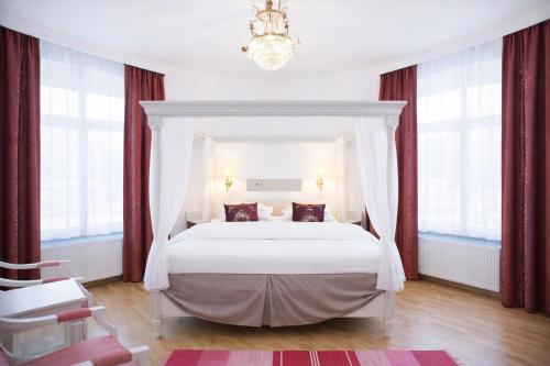 a bedroom with a bed with red curtains and a chandelier at Brommavik Hotel in Stockholm