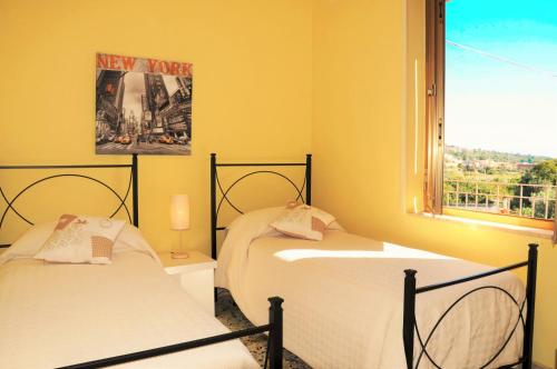- 2 lits dans une chambre jaune avec fenêtre dans l'établissement Al Vico dei Limoni, à SantʼAlessio Siculo