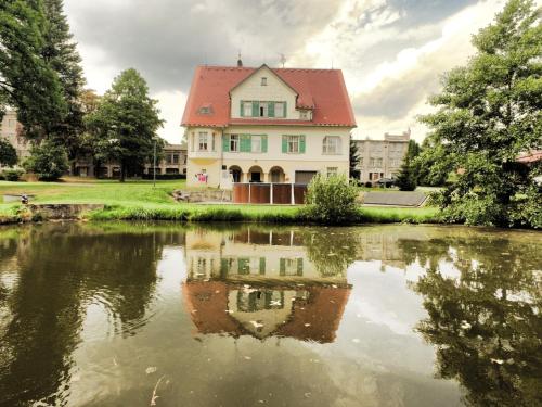a house with a reflection in a pond at Penzion Jungmannova in Šluknov