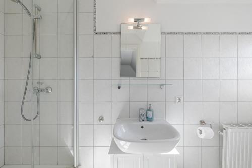a white bathroom with a sink and a shower at Meeresbrandung in Süderende