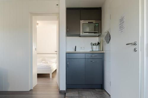 a kitchen with a blue cabinet and a microwave at Sonnenaufgang in Süderende