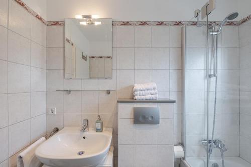 a white bathroom with a sink and a shower at Robbennest in Süderende