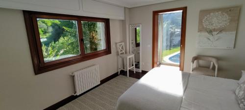 a bedroom with a white bed and a window at Villa El Castañal con Piscina Privada in Vigo