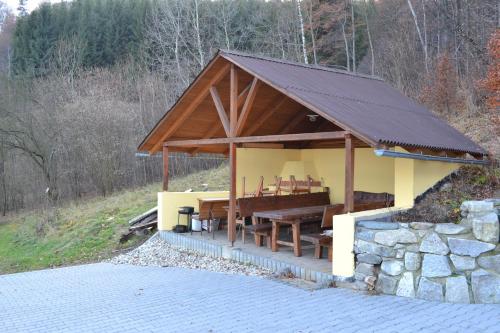 a pavilion with a table and a stone wall at Chata Eliška in Loučná nad Desnou