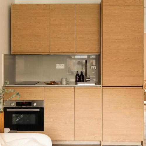 a kitchen with wooden cabinets and a stove at Bright Japandi 1BR Flat with Garden - Central Oxford in Oxford