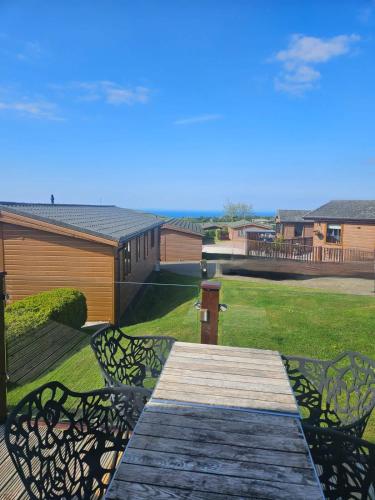 a wooden deck with two chairs on a yard at 3-Bed Ocean View Lodge - Parking & Terrace in Ilfracombe