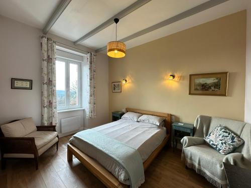 a bedroom with a bed and a chair and a window at La Verrerie de Guerlédan in Caurel