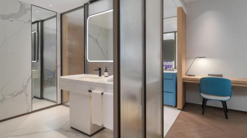 a bathroom with a sink and a desk with a blue chair at EVEN Hotel Xi'an High-Tech Zone by IHG in Xi'an
