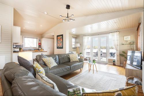 a living room with a couch and a tv at Keer Lodge a lakeshore haven Pine Lake Resort in Carnforth