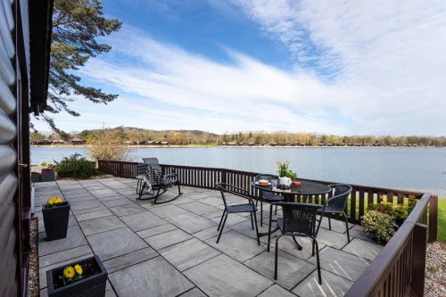 a patio with a table and chairs next to a lake at Keer Lodge a lakeshore haven Pine Lake Resort in Carnforth