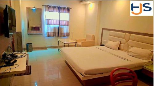 a bedroom with a bed and a tv and a chair at Hotel Jyoti Sanjay in Pūrnia