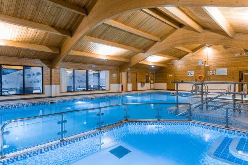 a large swimming pool with a wooden ceiling at Keer Lodge a lakeshore haven Pine Lake Resort in Carnforth