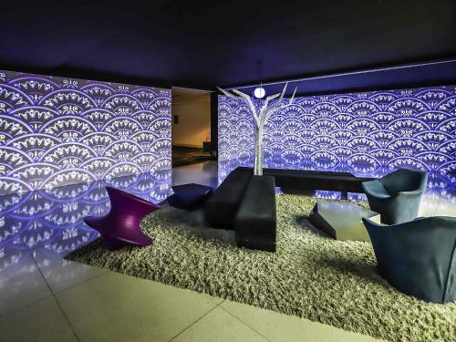 a room with purple walls and black chairs at ibis Styles Confins Aeroporto in Lagoa Santa