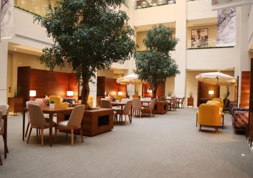 um átrio do hotel com mesas, cadeiras e árvores em Rafa - Al Nuzhah em Riyadh