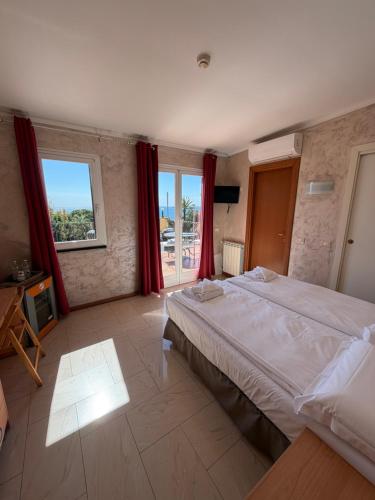 a bedroom with a large bed with red curtains at Hotel Villa Flora in Bogliasco
