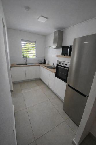 a kitchen with a stainless steel refrigerator and a window at Maison Dousè in Sainte-Rose