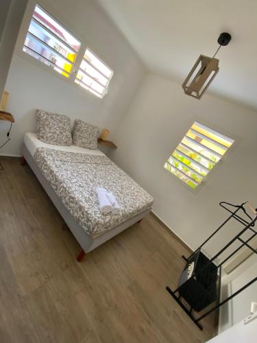 a bedroom with a bed and two windows at Maison Dousè in Sainte-Rose