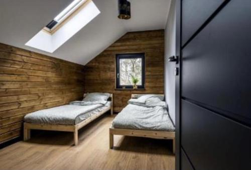 two beds in a room with wooden walls at Dom U Piepki in Zdunowice Małe