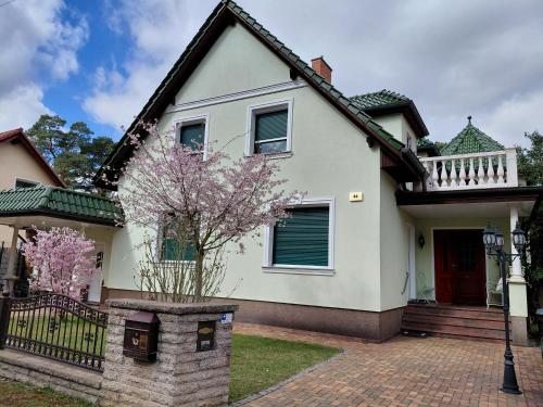 a white house with a tree in front of it at Ferienwohnung Baer 2 in Hoppegarten