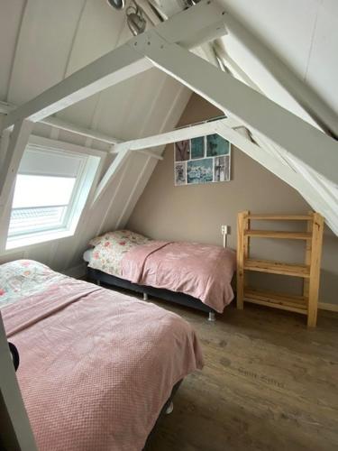 a attic bedroom with two beds and a window at B & Buitenlust in Schagerbrug