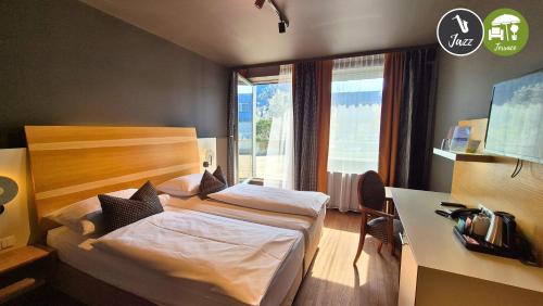 a hotel room with a bed and a desk and a window at arte Hotel Wien Stadthalle in Vienna